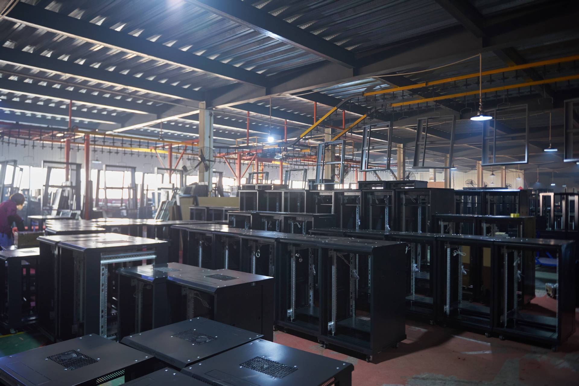 Rows of cabinet enclosures and suspended cabinet frames in a production workshop