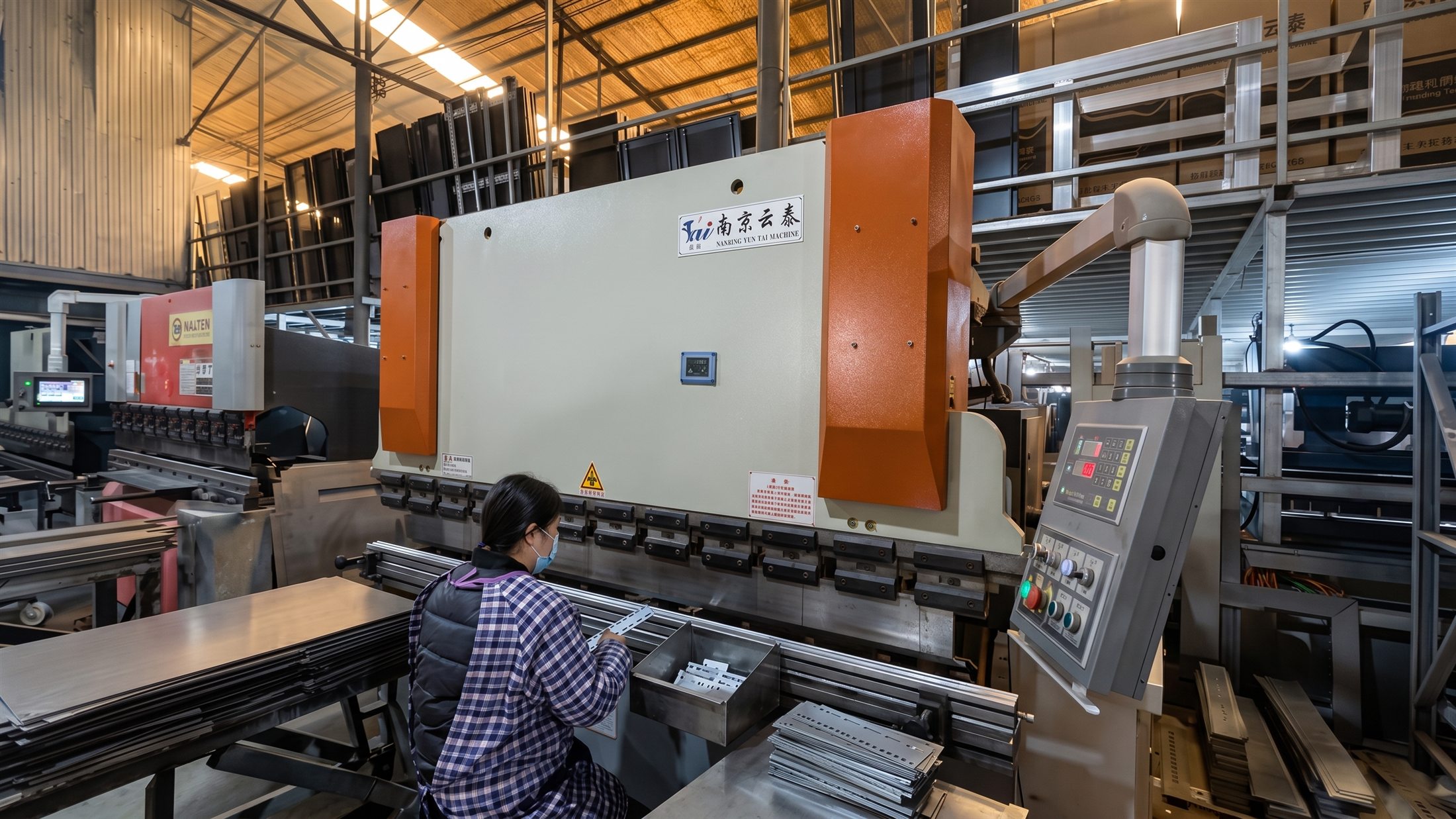 Operator forming sheet-metal cabinet parts at a press brake